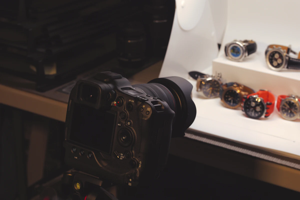 Kamera di atas tripod kecil diarahkan ke deretan produk yang sedang difoto untuk katalog