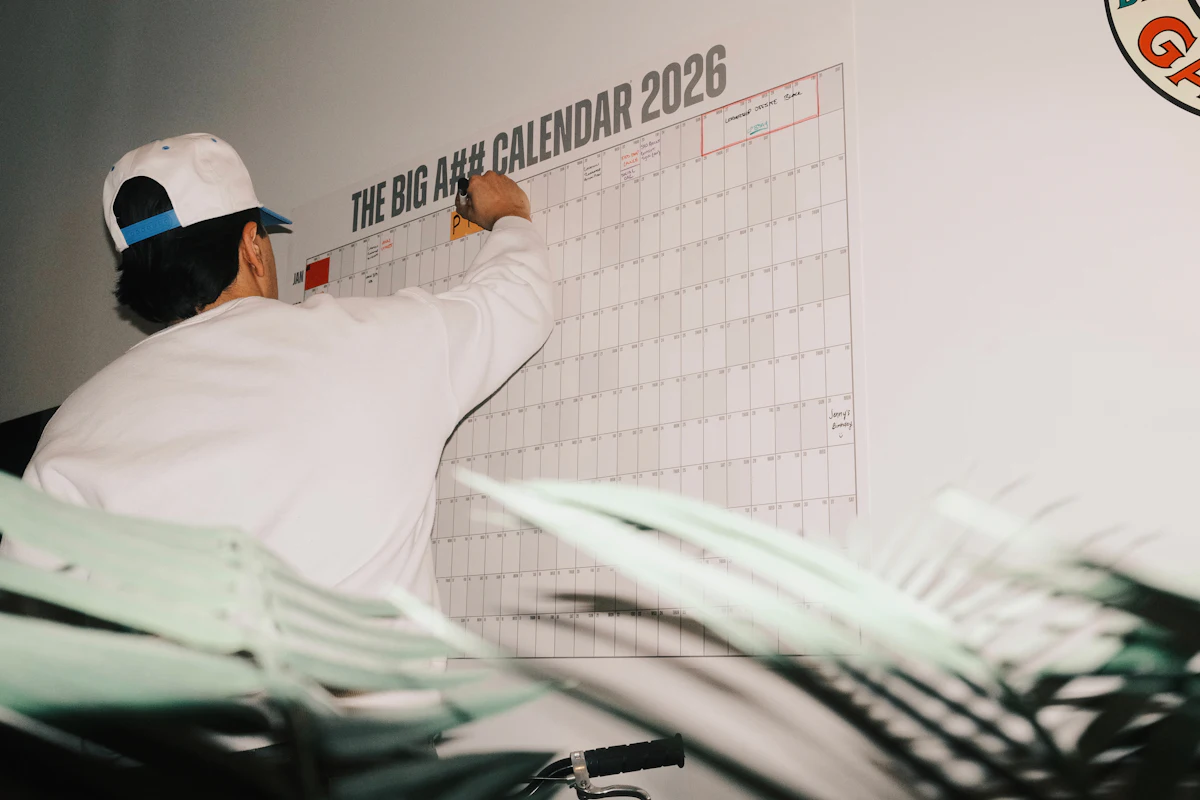 Pria menulis jadwal dengan spidol pada kalender dinding besar yang sudah berisi catatan dan tanda warna