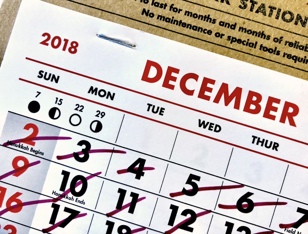 Kalender dinding satu bulan dengan beberapa tanggal dicoret spidol