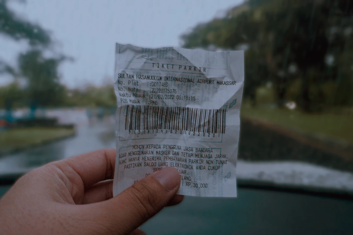 Tangan memegang selembar nota kertas bergaris barkode