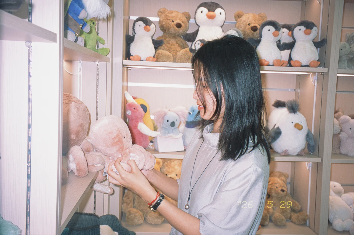 Pelanggan perempuan menilai mainan boneka yang dipegangnya di rak toko