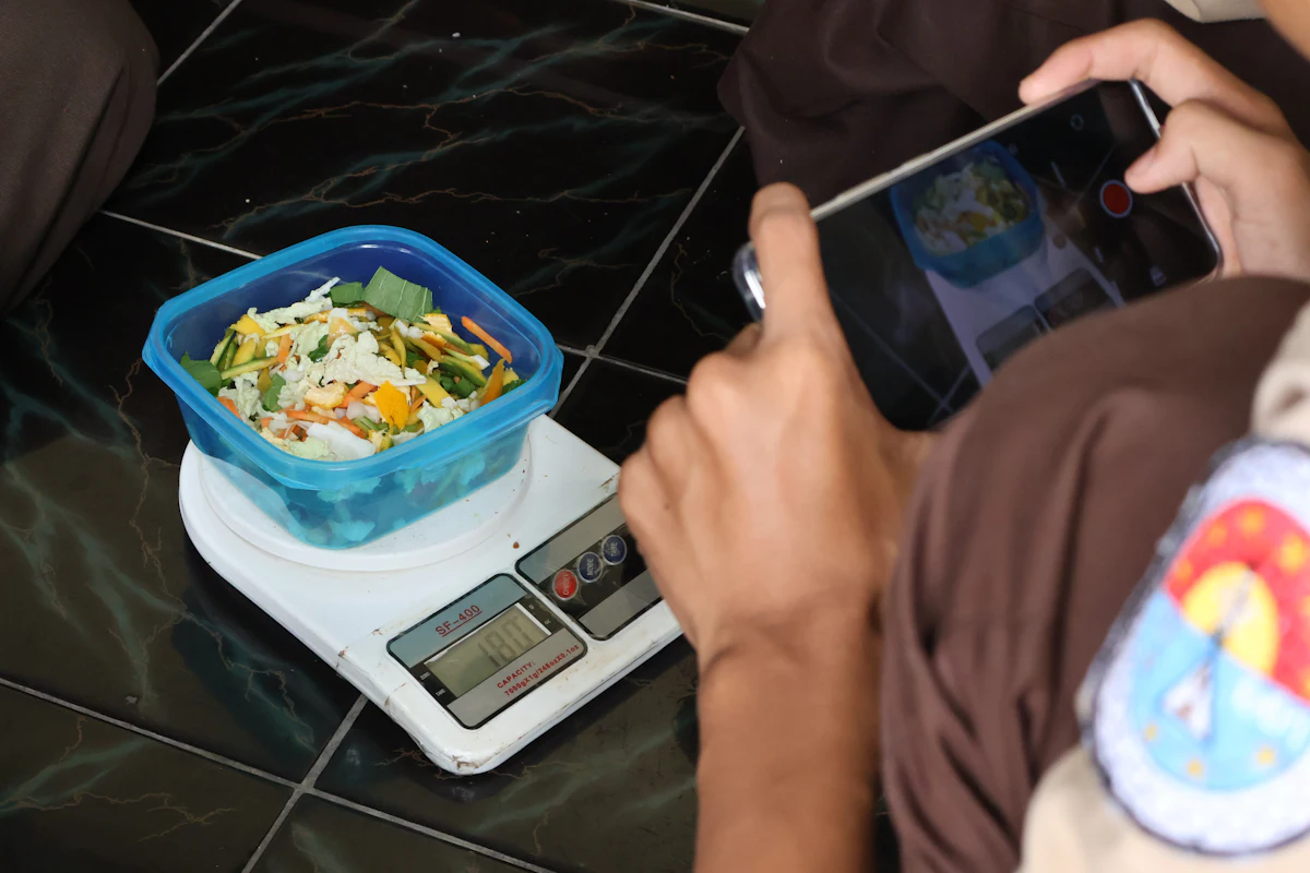 Makanan ditimbang di atas timbangan dapur digital dan difoto dengan ponsel