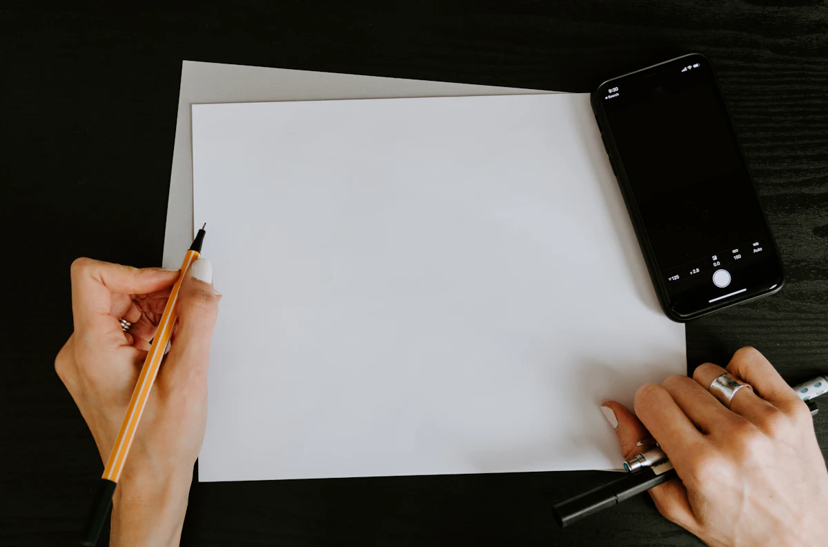 Tangan menuliskan daftar pendek di atas kertas memakai pulpen.