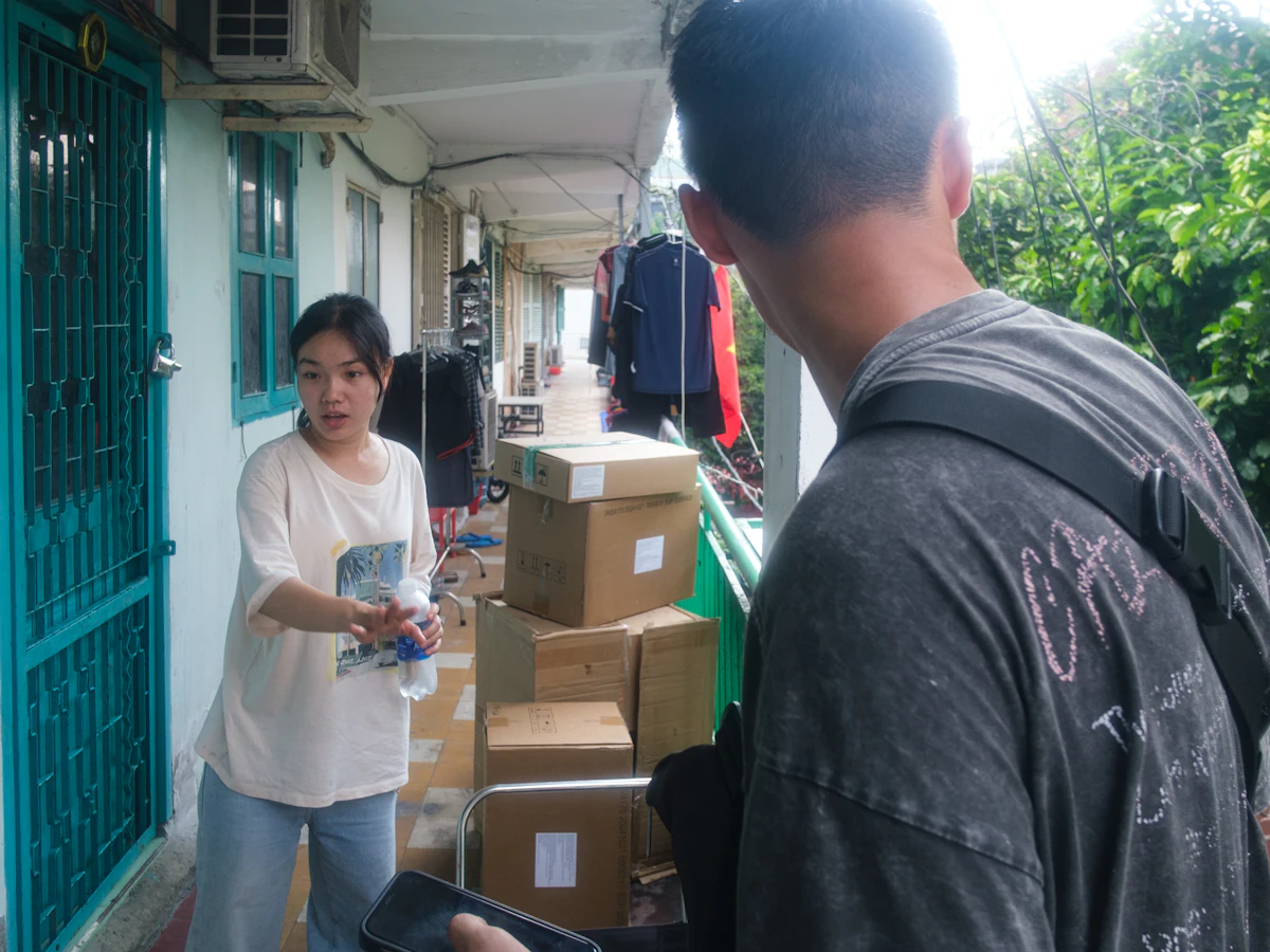 Tumpukan paket kardus berlabel pengiriman di atas troli diserahkan kepada penerima di koridor rumah