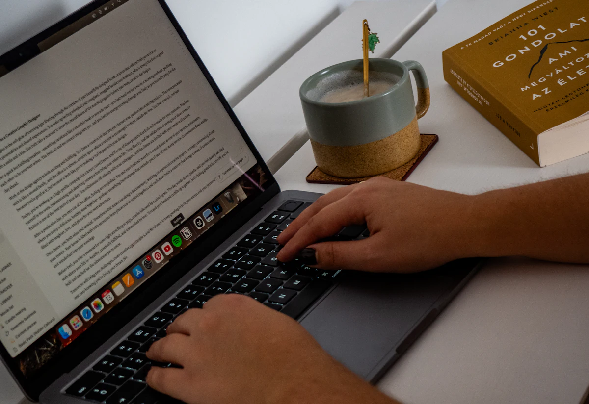 Tangan mengetik di keyboard laptop di atas meja kerja