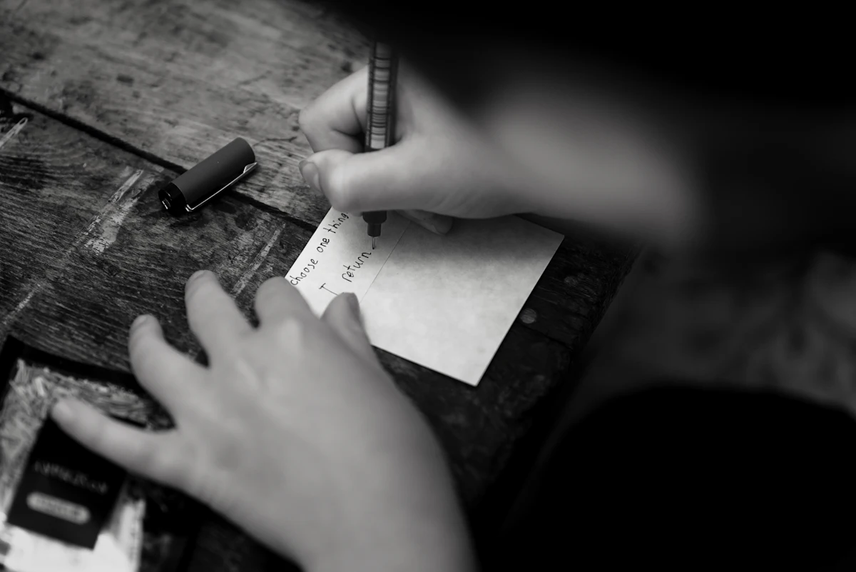 Tangan menulis catatan dengan pulpen di atas kertas di meja kayu