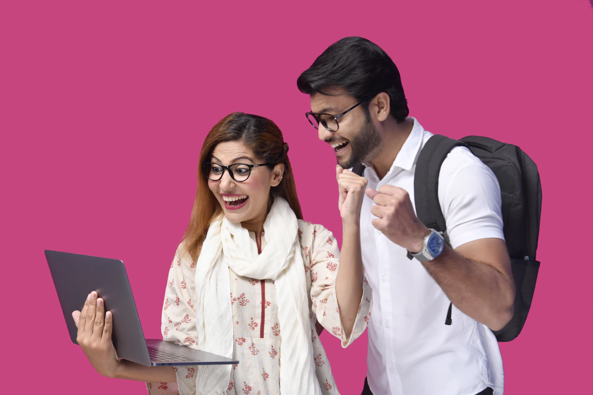 Staf berdiri menunjuk layar laptop yang sedang diperiksa pemilik usaha yang duduk di meja kerja
