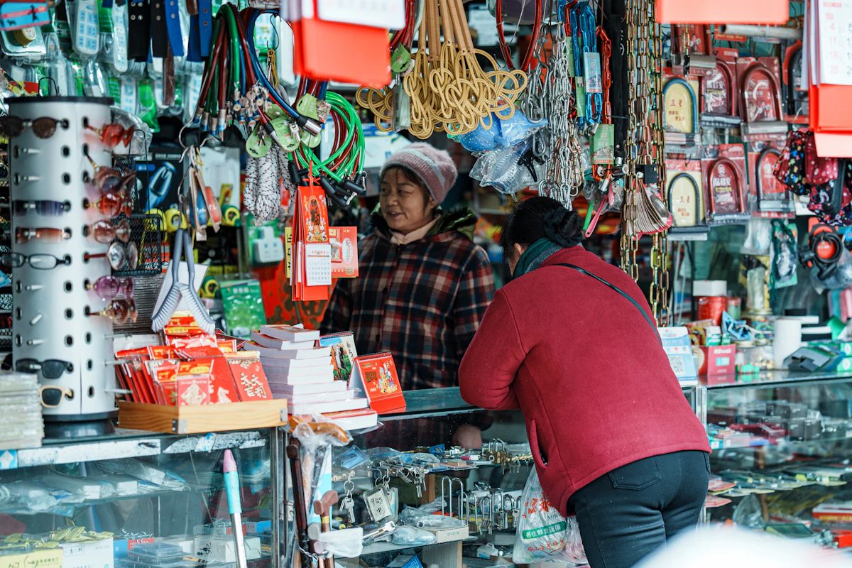 Dua orang perempuan melayani pembeli di balik meja sebuah lapak yang sedang ramai