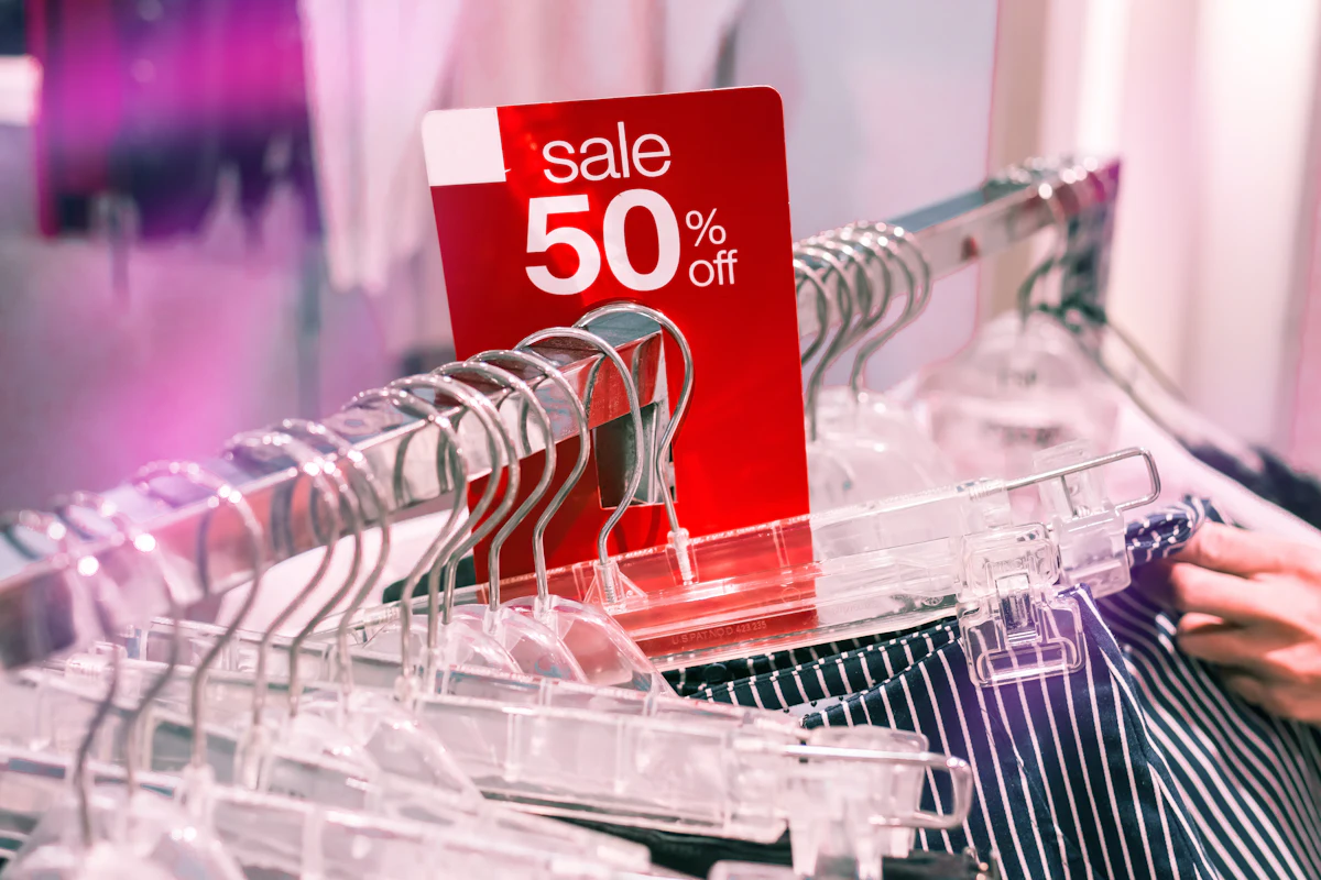 Label diskon merah terpasang di rak pakaian di toko