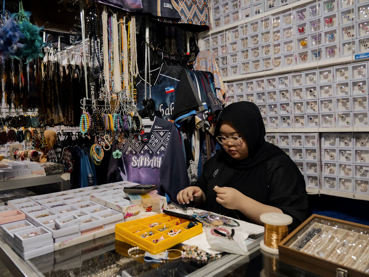Penjual perhiasan berhijab mengurus barang dagangannya di lapak pasar