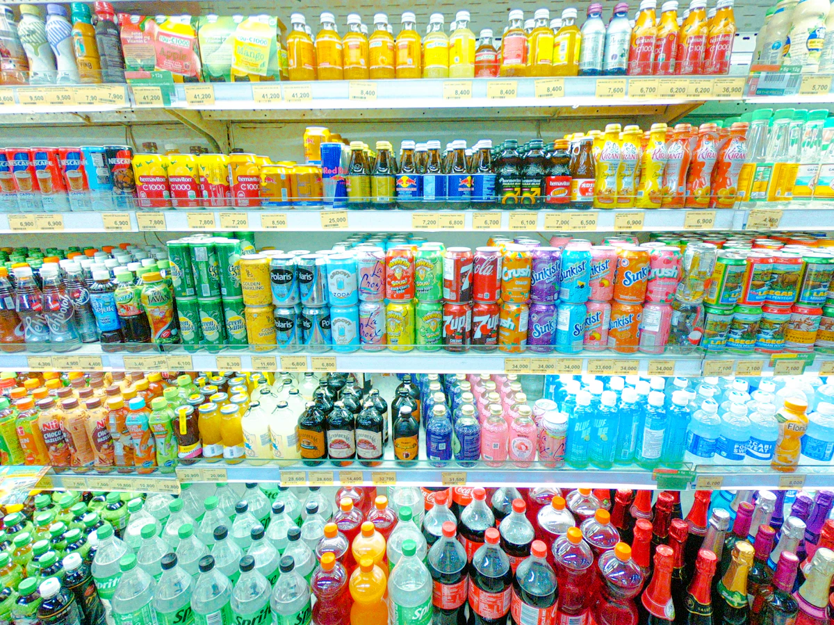Rak minuman minimarket Indonesia berjajar rapi dengan label harga rupiah di tepi rak