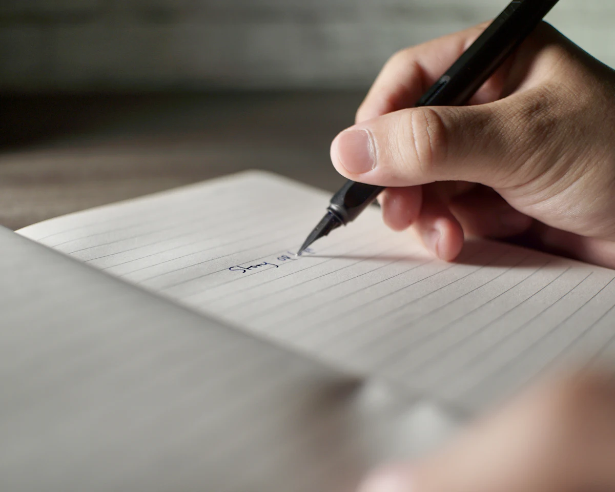 Seseorang menulis catatan tangan pendek dengan pulpen di atas kertas bergaris