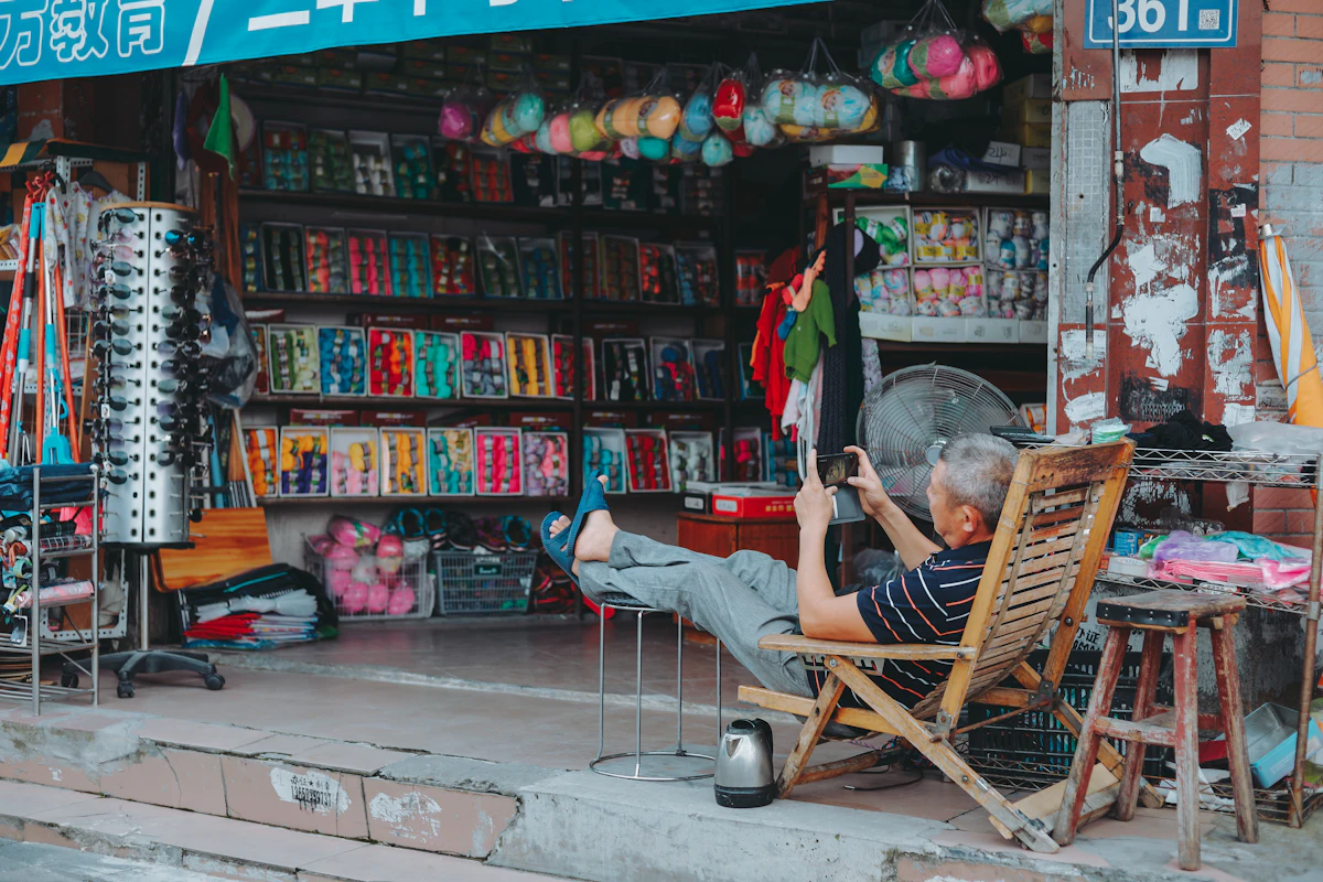 Pria duduk santai di kursi sibuk dengan ponselnya