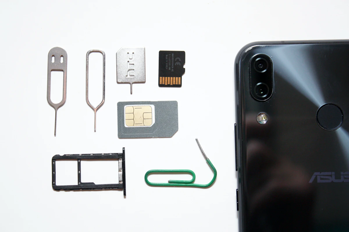 Ponsel, kartu SIM, tray, dan pin ejector tergeletak berdampingan