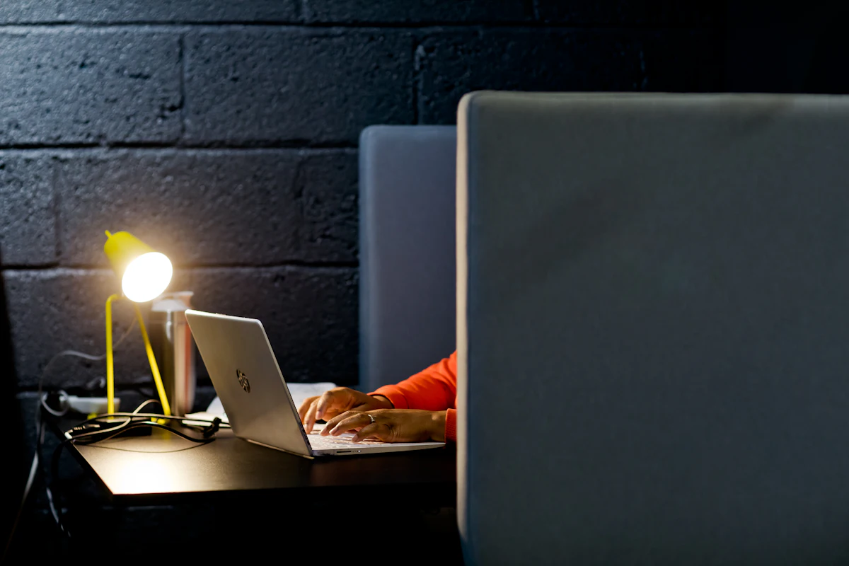 Seseorang mengerjakan laptop sendirian di ruangan gelap pada malam hari